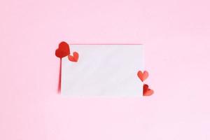 White envelope with mini heart shape on pink background photo