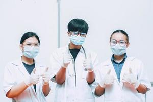 Group of doctor wearing protective mask and uniform doing thumb up pose and looking to the camera photo