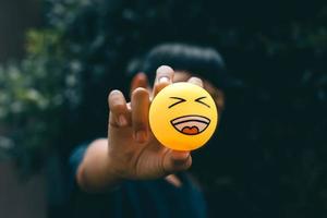 Laugh emoticon in a boy hand isolated on black background photo