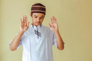 Portrait of young asian muslim man doing salah with raising his hand, takbiratul ihram photo