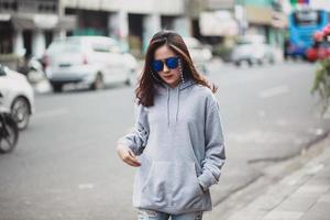 Beautiful woman wearing sweater hoodie and sunglasses walking on the city street photo