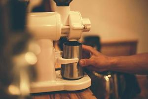 mano de barista usando molinillo de café foto