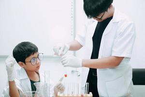 Teacher and student scientists in protective glasses making experiment in lab photo