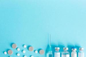 Syringe and vial drug with round tablet as a border on a blue background with copy space photo