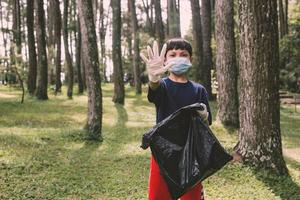 un niño con un gesto de alto en la mano, deja de tirar basura, salva el concepto de la tierra foto