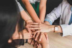Close up top view of young business people putting their hands together. Stack of hands. Unity and teamwork concept. photo