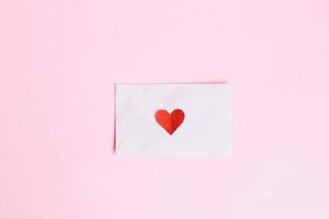 Top view of mini red heart shape on envelope with pink background photo