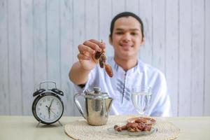 Dates on muslim man hands with clock showing 6 o'clock for iftar time photo