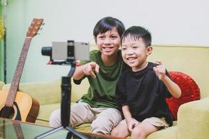 Two asian children youtuber smiling and looking to a smart phone while making video content photo