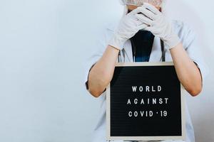 Cropped shot of doctor are covering her face with quote on letter board says World Against Covid 19 isolated on white background. Campaign against coronavirus with copy space photo