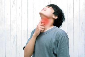 Throat pain. Asian male holding her inflamed throat. photo