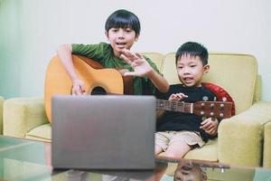 dos niños músicos haciendo transmisión en vivo y mostrando gestos saludan a la audiencia en una computadora portátil foto