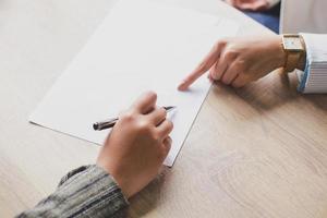 Hand of two woman on blank paper in work desk at office, making a deal, agreement signing, free space, copy space, place for text. photo