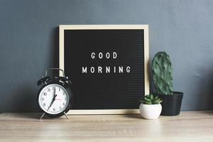 GOOD MORNING quote on blackboard with classic alarm clock, cactus and succulent on wooden table photo