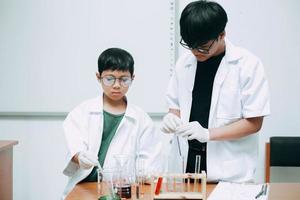 profesor científico y estudiante en gafas protectoras haciendo experimentos en laboratorio foto