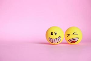 Smiley emoticon with laugh emoticon isolated on pink background with copy space photo