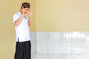 Side view of young asian muslim man doing salah with raising his hand, takbiratul ihram photo