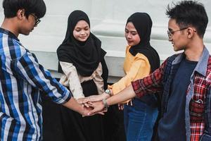 Group of young people putting their hands on top of each other. Close up image of students friends making a stack of hands. Trust and friendship concept
