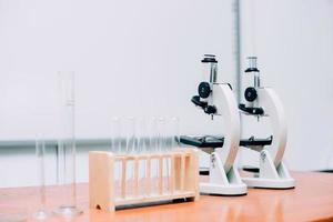diferentes vasos de precipitados de laboratorio vacíos y cristalería con microscopio sobre la mesa en el laboratorio. día nacional de la ciencia, día mundial de la ciencia