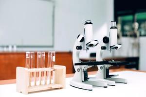 microscopio de metal de laboratorio y tubos de ensayo vacíos en la mesa. día nacional de la ciencia, día mundial de la ciencia foto