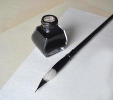 Ink bottle with brush for painting calligraphy on white photo