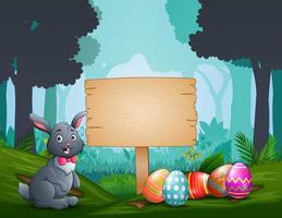 Happy bunny with Easter eggs around him by a wood sign board vector