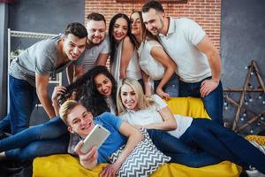 agrupar a hermosos jóvenes haciendo selfie en un café, mejores amigos niñas y niños juntos divirtiéndose, planteando un concepto de estilo de vida emocional foto