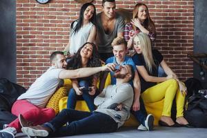 retrato grupal de niños y niñas multiétnicos con ropa colorida de moda sosteniendo a un amigo posando en una pared de ladrillo, gente de estilo urbano divirtiéndose, conceptos sobre el estilo de vida de la unión juvenil foto