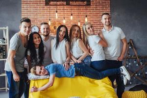 Group portrait of multi-ethnic boys and girls with colorful fashionable clothes holding friend posing on a brick wall, Urban style people having fun, Concepts about youth togetherness lifestyle photo