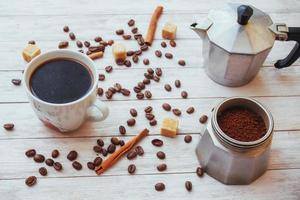 granos de café y una taza de café en la mesa al fondo