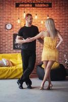 Young couple dancing latin music Bachata, merengue, salsa. Two elegance pose on cafe with brick walls photo