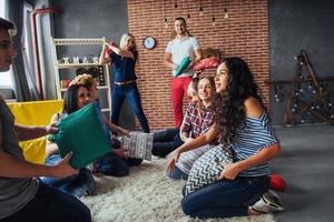 Crazy young best friends fighting pillows at home. Mixed race group of people. Concept  entertainment and lifestyle photo