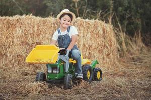 Child playing with toy tractor on meadow photo