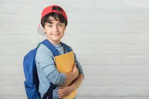 niño feliz con mochila y cuaderno, regreso a la escuela foto