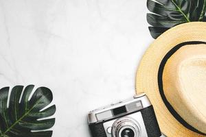 Straw hat with green tropical leaves and vintage photo camera with space for text.Vacation travel Concept