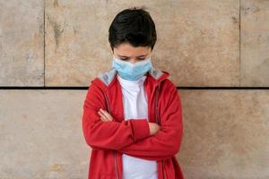 sad and angry kid with protective surgical mask photo