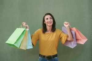 mujer joven sonriente sosteniendo bolsas de compras
