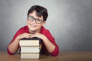 smiling little boy leaning on books on a table photo