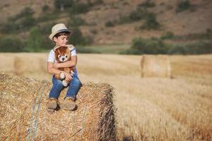 Boy hugging teddy bear in the wheat field photo