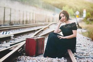 mujer feliz con una maleta en las vías del tren