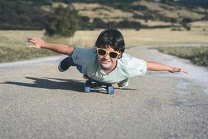 happy kid with skateboard and sunglasses on the road photo