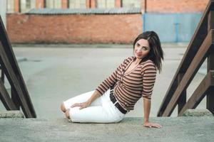 smiling young woman sitting on the street photo