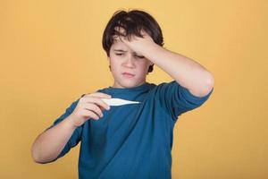 diseased child with a thermomether, measuring his fever photo