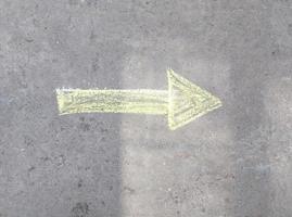 the arrow is drawn in chalk on the asphalt. indicates the direction.