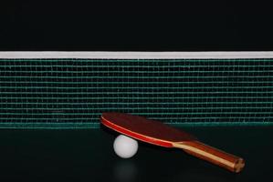 Pelota de raqueta de tenis de mesa y net en la mesa de tenis de mesa closeup recto foto