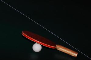 pelota de tenis de mesa con raqueta en la línea central foto