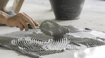 The tile glues the tile to the floor with a glue applied by a notched trowel photo