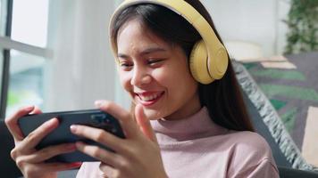 femme assise sur un canapé en tenant le smartphone pour regarder des films sur l'application mobile et une journée de détente dans la maison. video