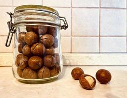 Macadamia nut in a transparent jar and nuts nearly close-up photo