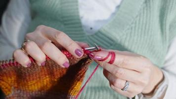 jovem tricota com bolas coloridas de lã e agulhas video